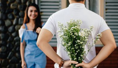 man holding baby s breath flower in front of woman standing near marble wall