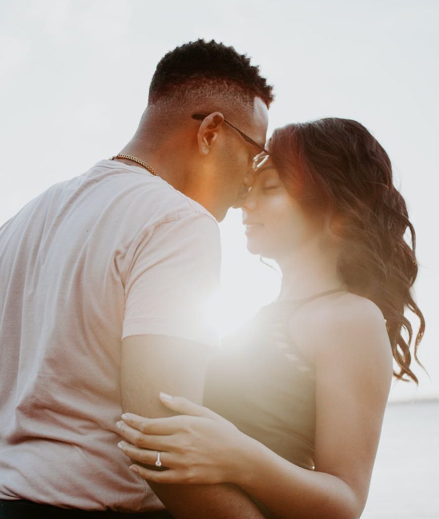 man wearing white shirt kissing woman in her nose
